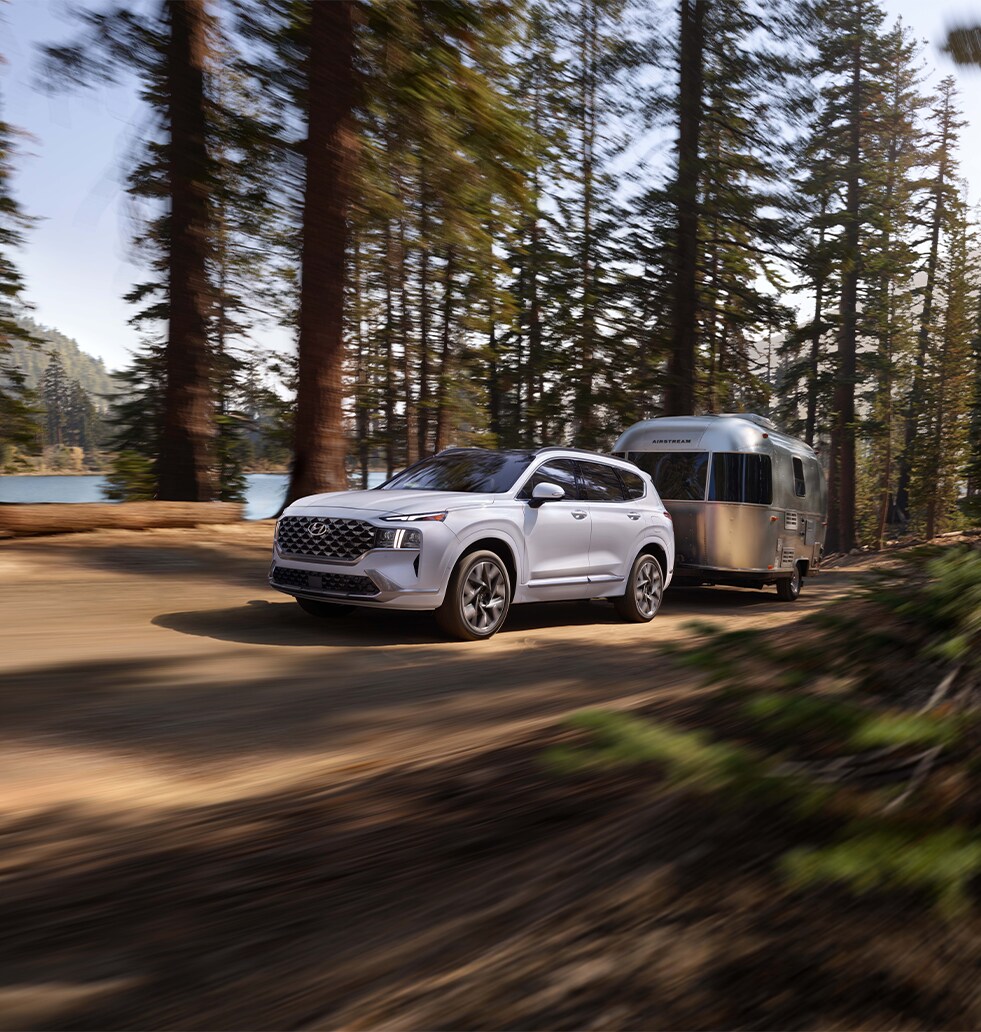 2023 Hyundai Santa Fe at West Broad Hyundai | White 2023 Santa Fe towing a trailer while driving down a off road road
