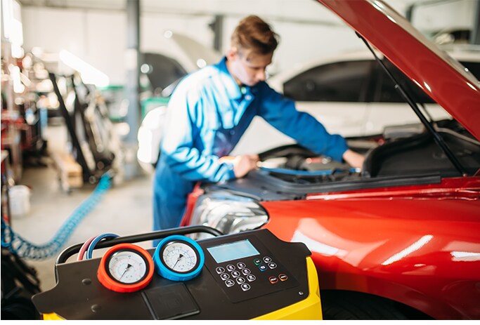 How to Get Your Car Summer Ready at West Broad Hyundai in Henrico, VA | Mechanic in blue uniform charging car A/C using a A/C machine