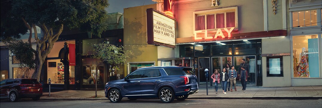 Compare the 2021 Hyundai Palisade vs. the 2021 Toyota Highlander at West Broad Hyundai | Parked outside theater during night