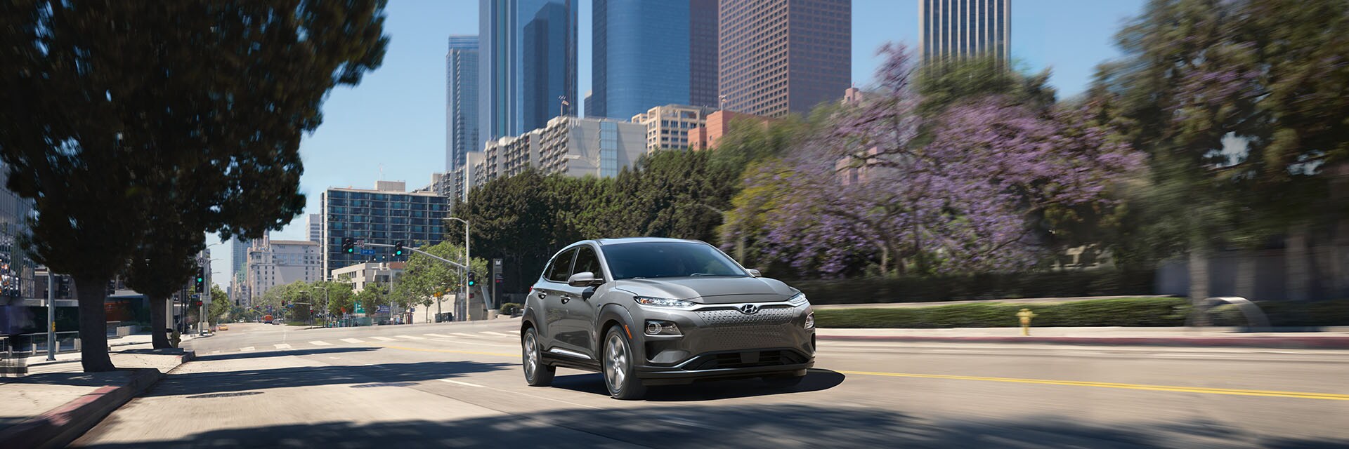 Tips for spring cleaning your car at West Broad Hyundai in Henrico, VA | Front View of Silver Hyundai Kona-EV Ultimate Driving in City with Trees