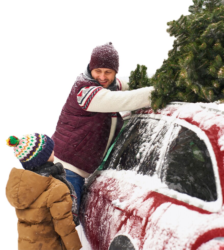 How to Prevent your Vehicle from Fogging Up At West Broad Hyundai in Henrico, VA | Man in red vest is strapping up Christmas tree on top of car roof with his son in the winter