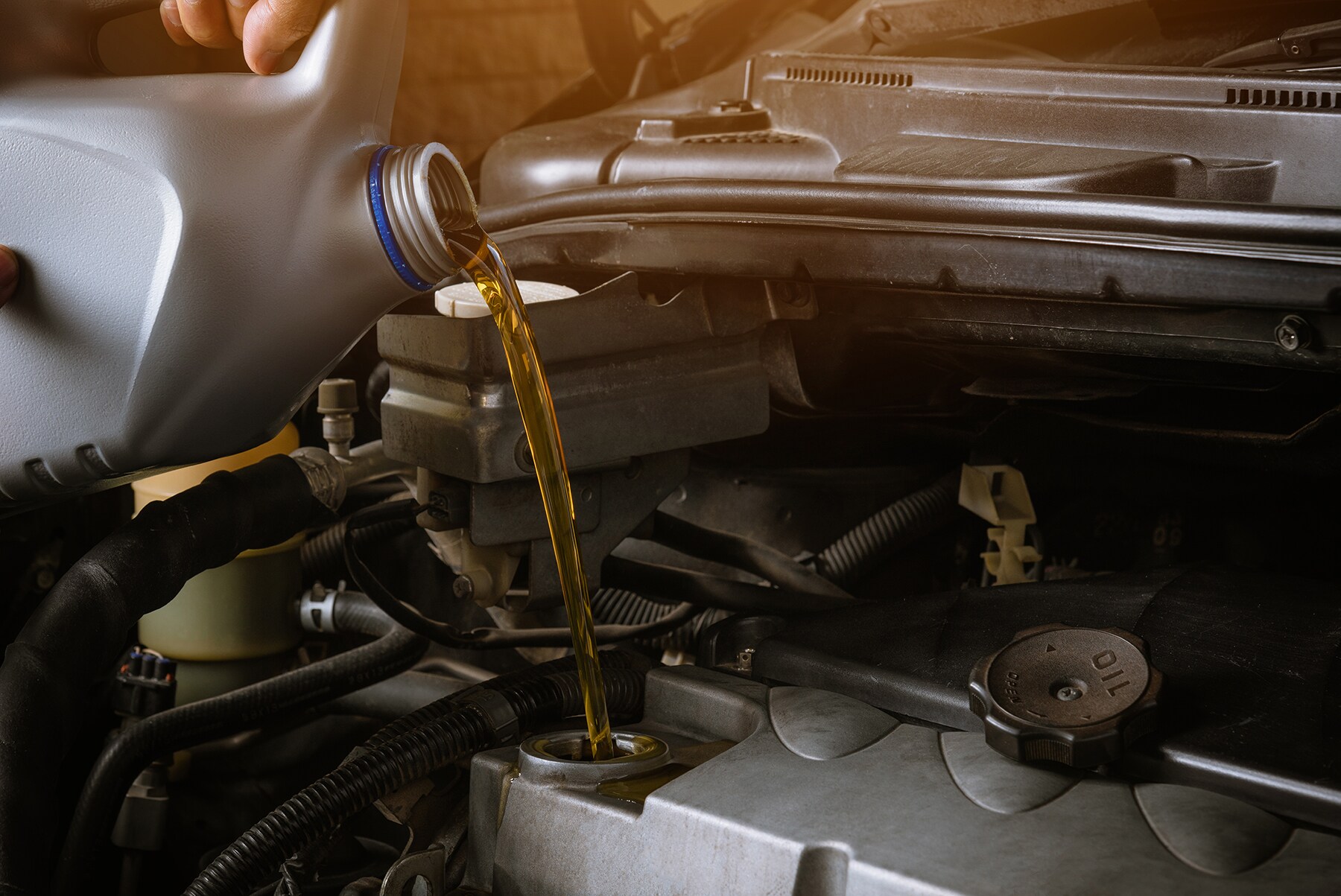 Difference between synthetic oil & conventional oil at West Broad Hyundai | Mechanic pouring fresh oil into engine