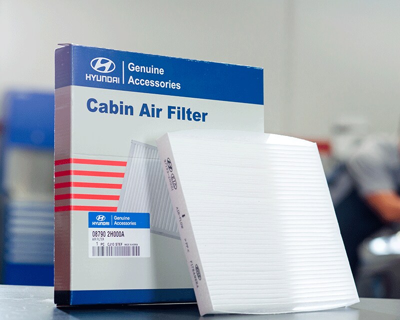 3 Main Benefits of Using OEM parts for your vehicle at West Broad Hyundai in Henrico, VA | Hyundai Genuine Accessories Cabin Air Filter Box with Cabin Air Filter Propped Against it Sitting On Table