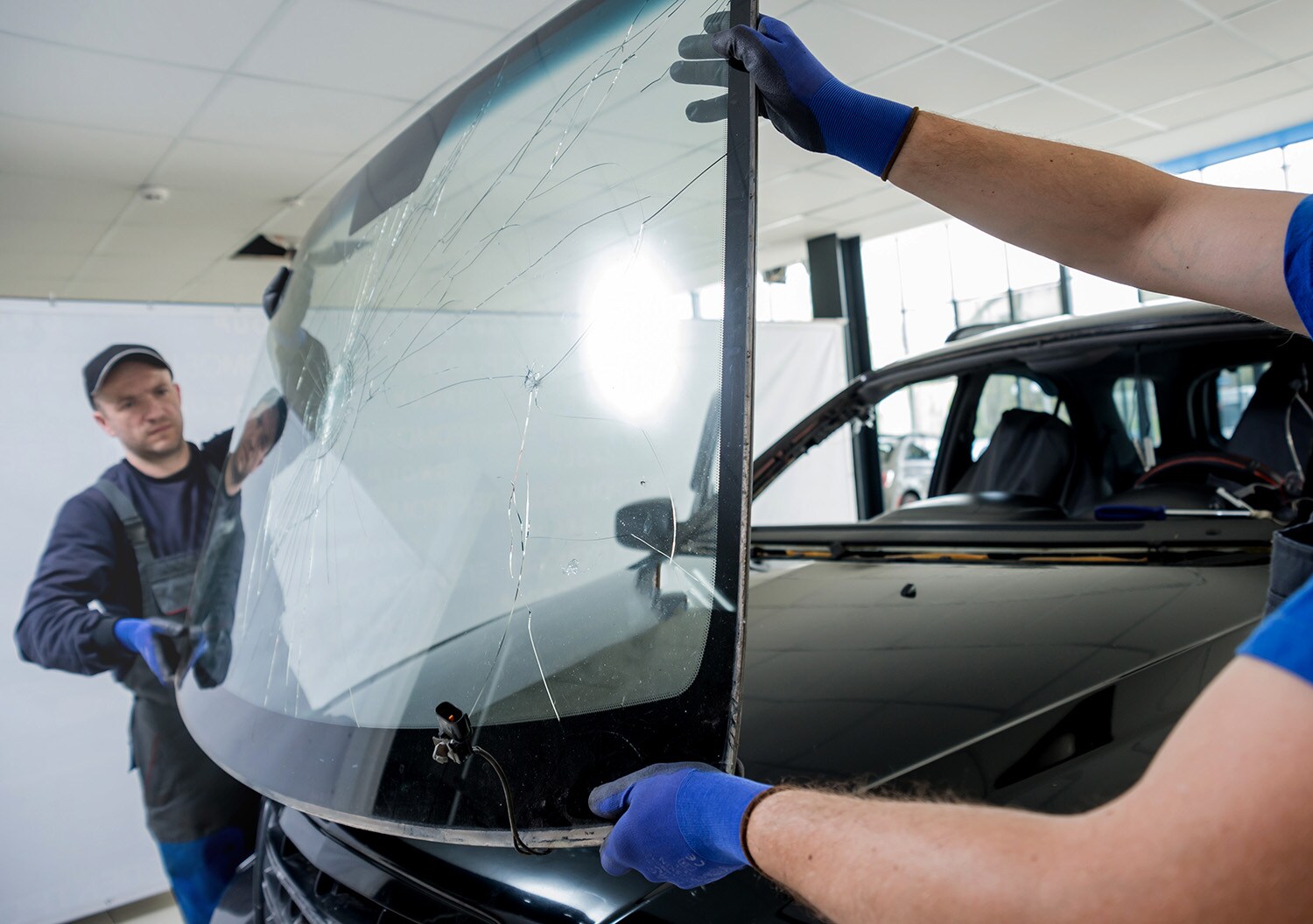 Why You Shouldn't Drive Around with a Chipped Windshield at West Broad Hyundai in Henrico, VA | Hyundai service technicians replacing cracked windshield with a brand new one