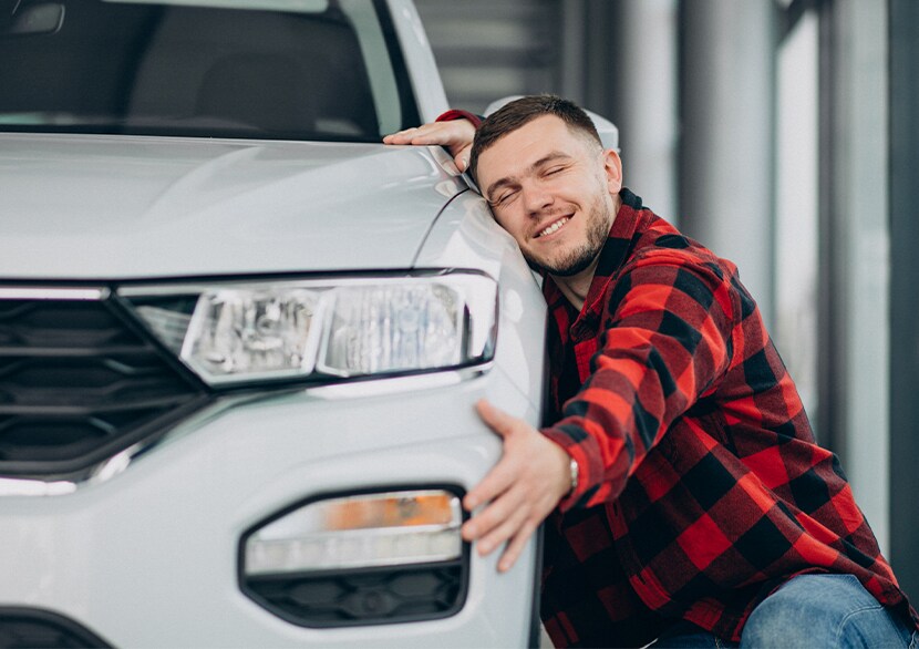 Why drivers should consider an extended warranty on their Hyundai at West Broad Hyundai | Man in red shirt hugging his new white car
