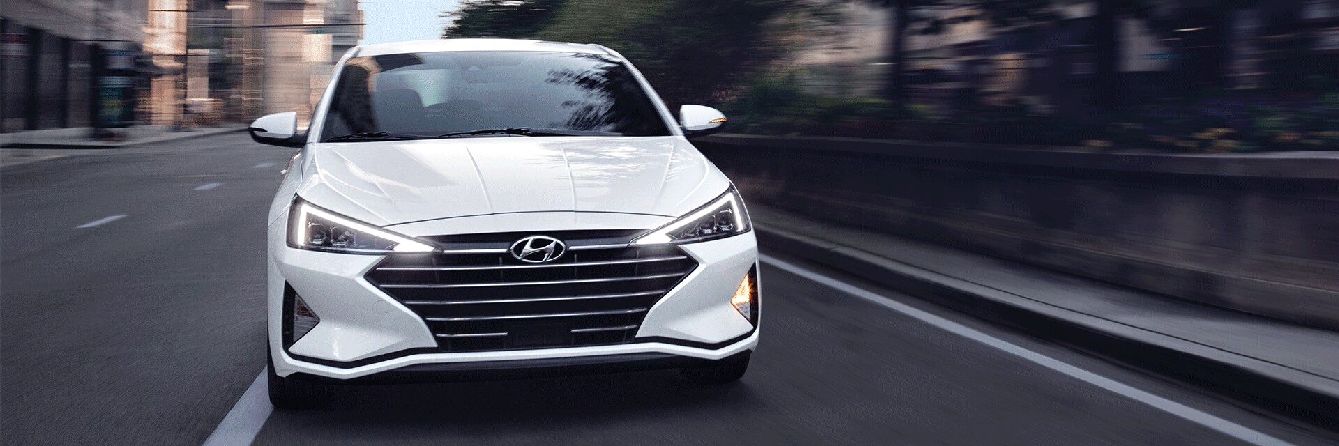 Things to Check When Buying a Used Car | West Broad Hyundai in Henrico, VA | Front View of 2021 White Hyundai Elentra Limited Ultimate Driving Fast in the Ciy