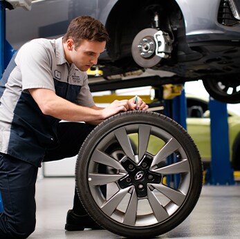 Brake replacement and Safety at West Broad Hyundai | hyundai Mechanic inspects tire on ground