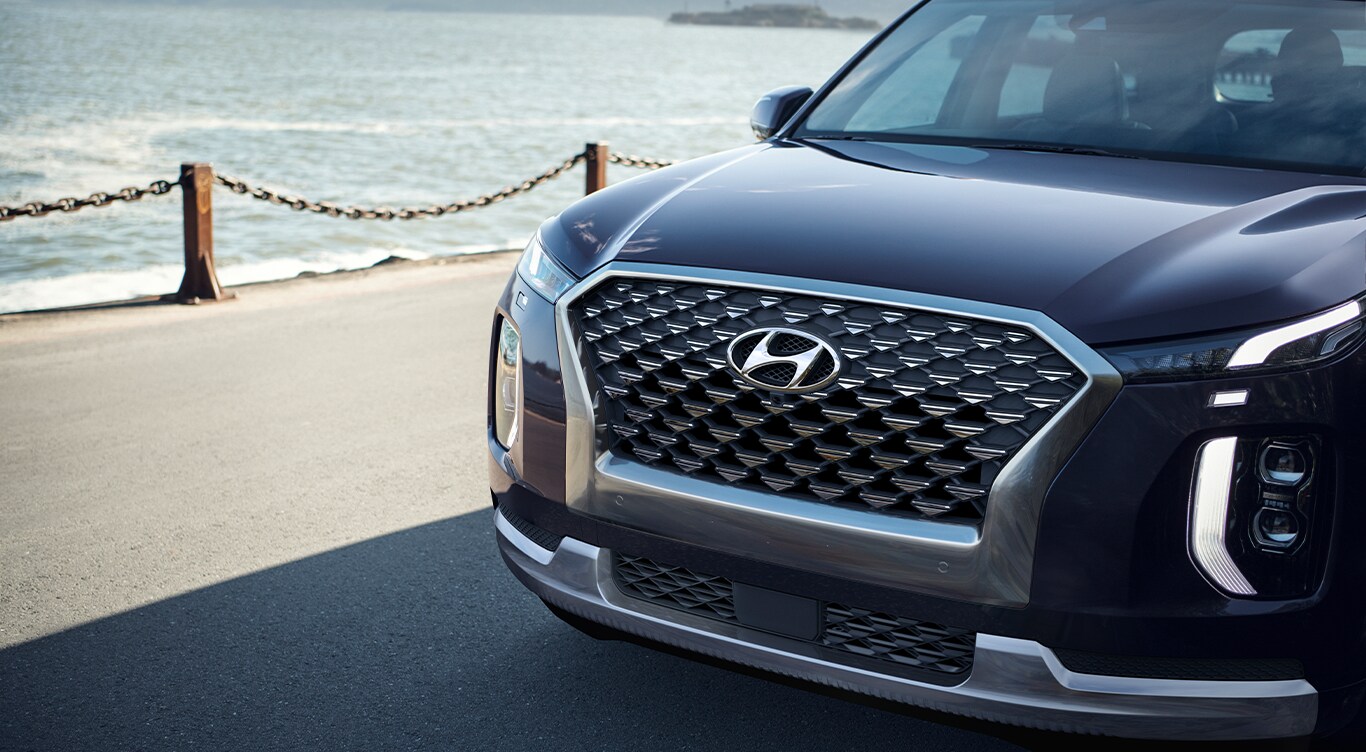 Android Auto vs. Apple CarPlay at West Broad Hyundai in Henrico, VA | Front bumper of a dark blue 2023 Hyundai Palisade parked beside the beach
