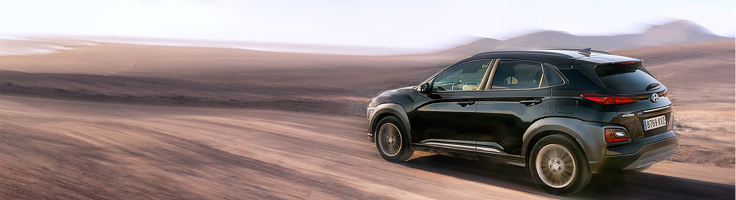 How to Get Your Car Summer Ready at West Broad Hyundai in Henrico, VA | Black Hyundai Kona driving on dirt road with mountains in the background