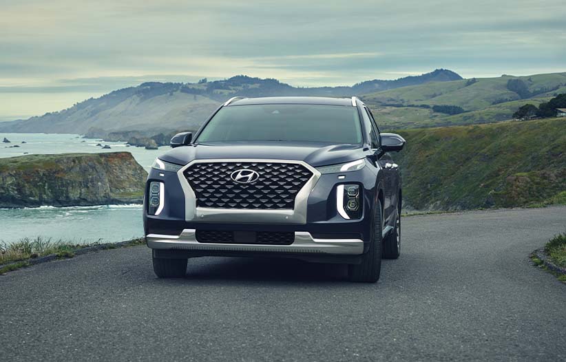 Model Features of the 2022 Hyundai Palisade at West Broad Hyundai | Blue 2022 Hyundai Palisade Driving Around Bend with Lake in Distance