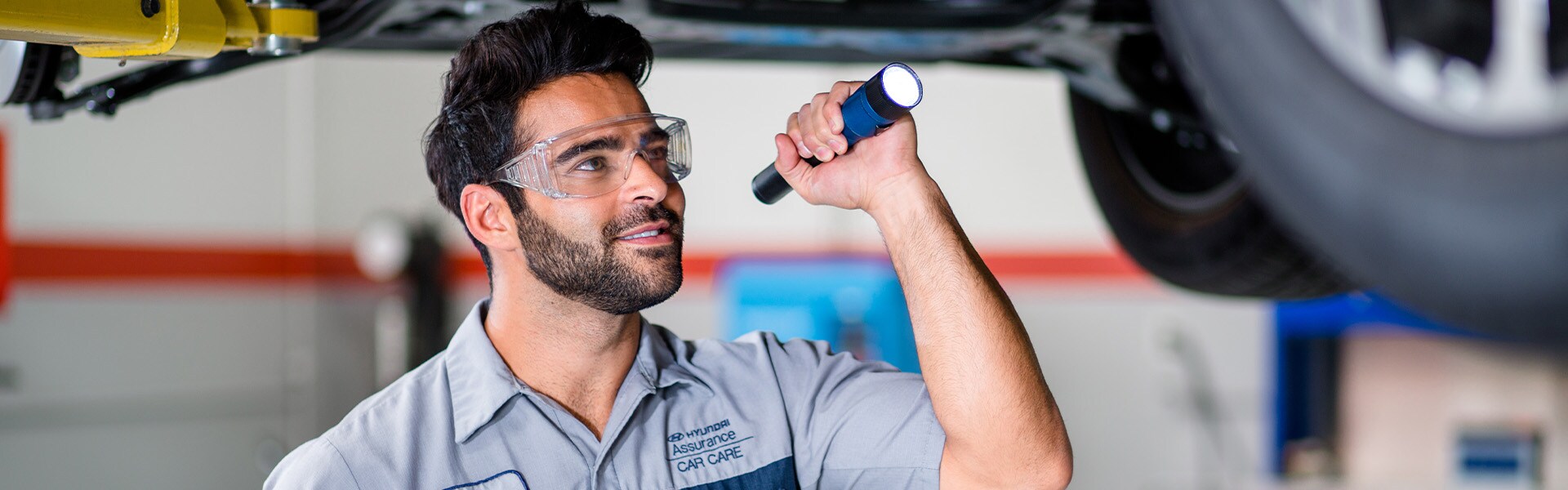 What is included in a Multi-Point Inspection? | West Broad Hyundai in Richmond | Hyundai Service Advisor Inspecting Undercarriage of Hyundai Vehicle
