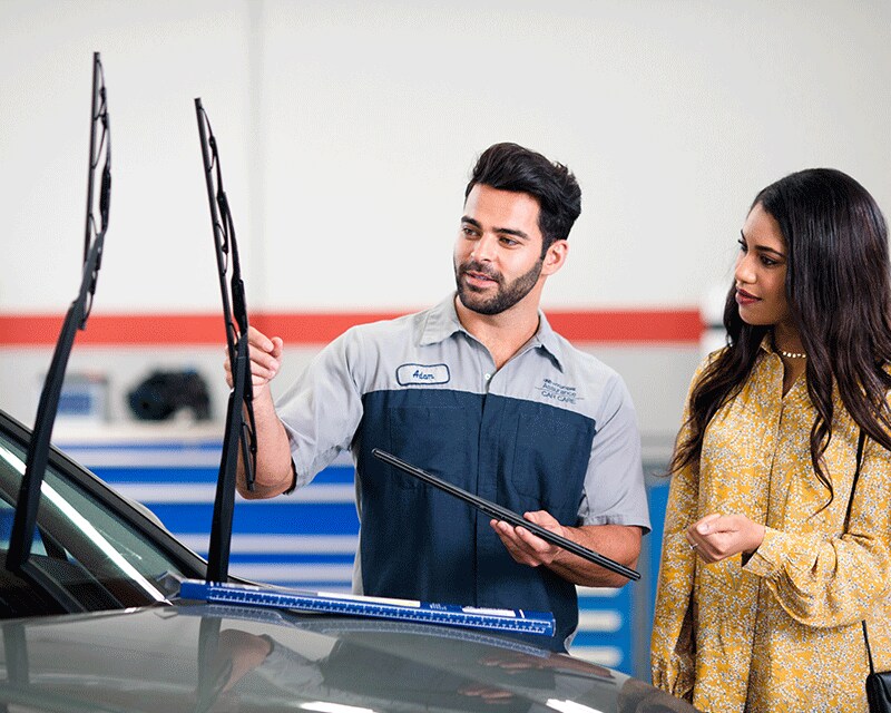 Basic Car Maintenance and Servicing Checklist | West Broad Hyundai | Hyundai Technician Holding Window Wiper Showing Customer Wiper Options while Window Wipers are Pulled up on Car
