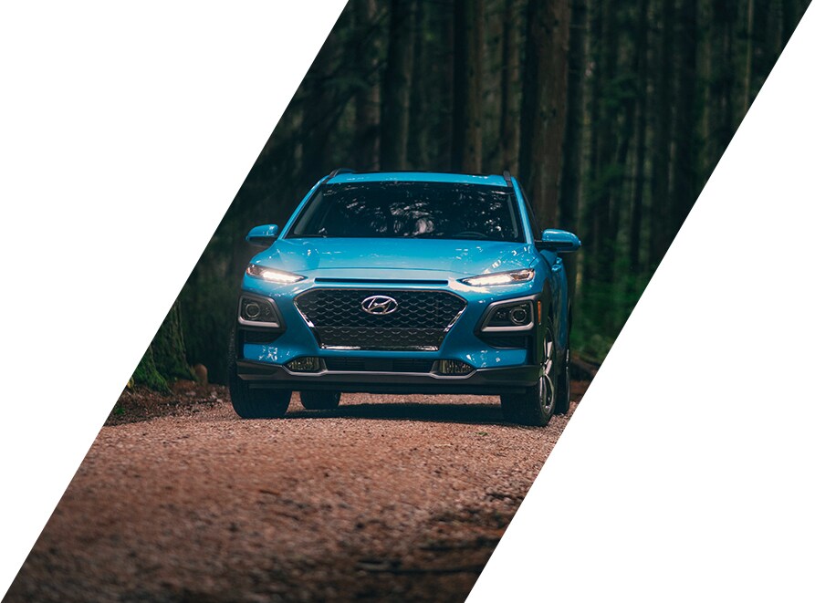 West Broad Hyundai is a Hyundai Dealership in Richmond near Short Pump, VA | Blue Hyundai Kona SUV Driving Through Forest
