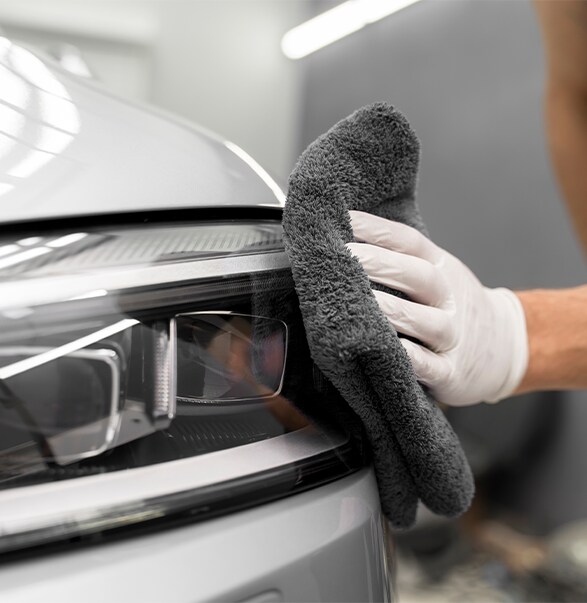 How to Prepare to Trade in Your Car | West Broad Hyundai in Henrico, VA | Person with white gloves using a dark grey microfiber towel to dry off their car