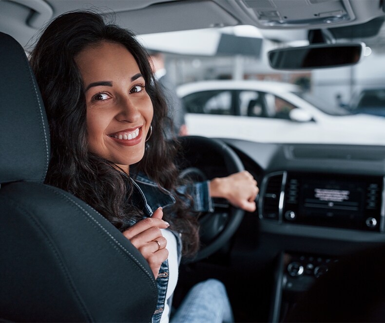 Enjoy A Test Drive At West Broad Hyundai in Henrico, VA | Woman sitting in drivers seat and turning back to the rear seat view while smiling