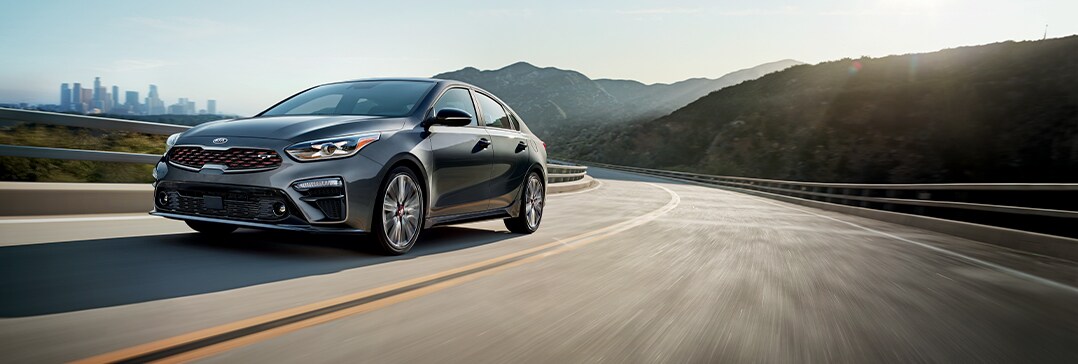Compare the 2021 Kia Forte vs. the 2022 Toyota Corolla at West Broad Kia | Kia Forte driving fast on back road