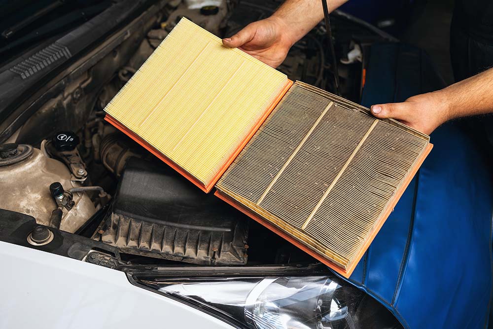 Cabin air filter replacement at West Broad Kia | Kia service technician comparing old and dirty air filter to a new and clean air filter