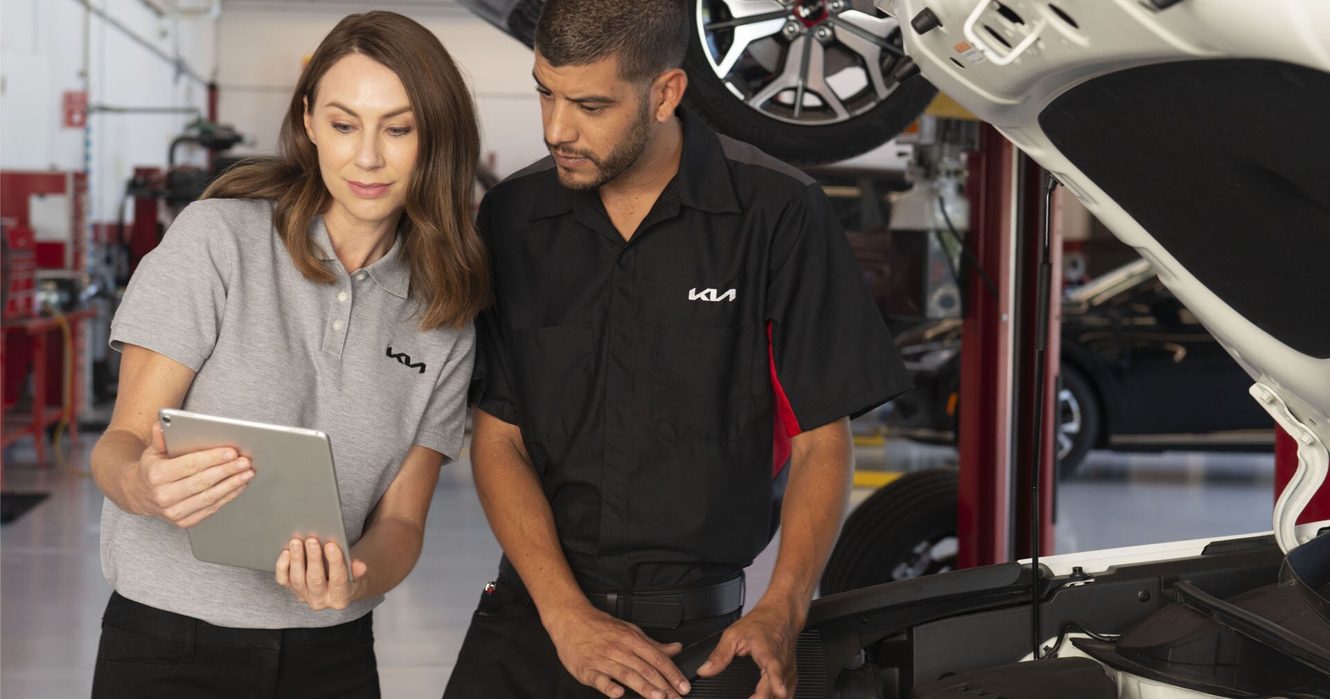 What is included in a Multi-Point Inspection? | West Broad Kia in Richmond | Service Technicians Looking at Tablet Standing Next to Car