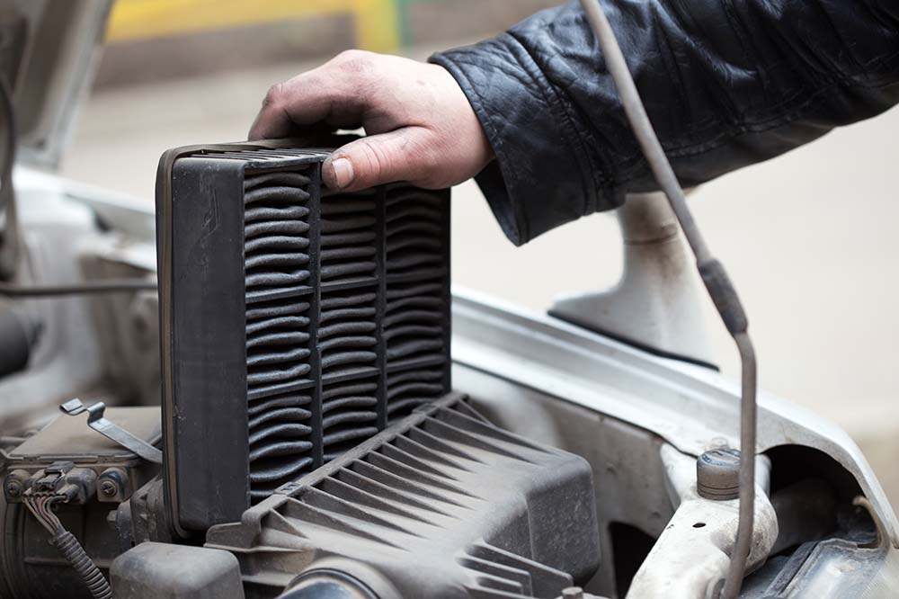 Cabin air filter replacement at West Broad Kia | Man taking out dirty air filter from car