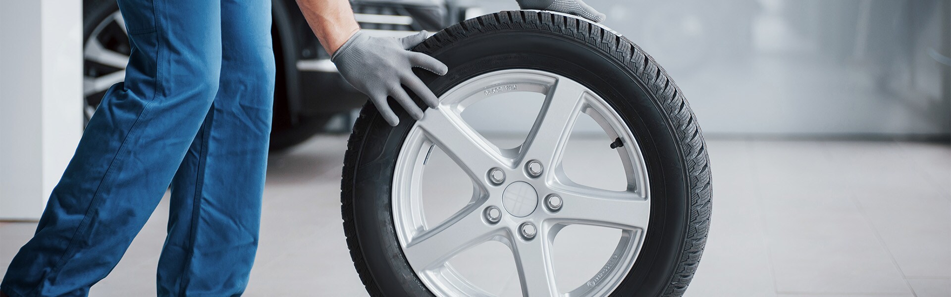 what different tire options are available at West Broad Kia in Richmond | Service Advisor Rolling Tire on Floor of Service Bay