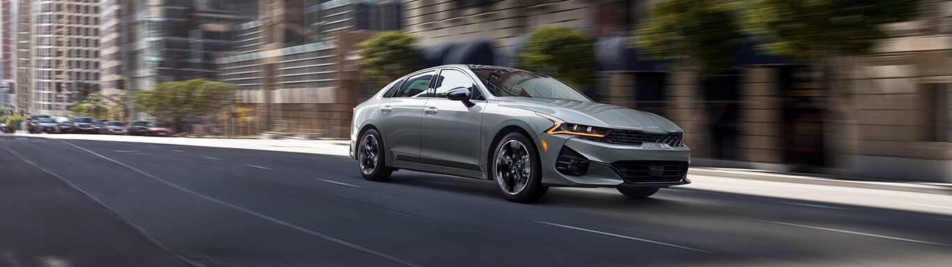 Best MPG At West Broad Kia in Henrico, VA | Grey 2023 Kia K5 driving down city road during the day