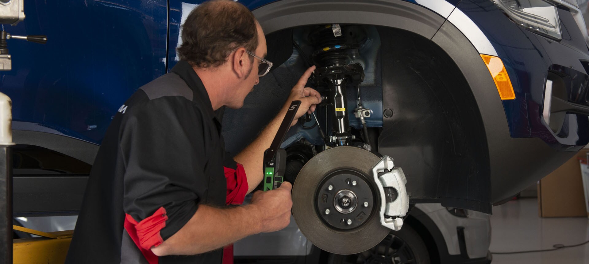 What is included in a Multi-Point Inspection? | West Broad Kia in Richmond | Service Technician Inspecting Car Under Wheel