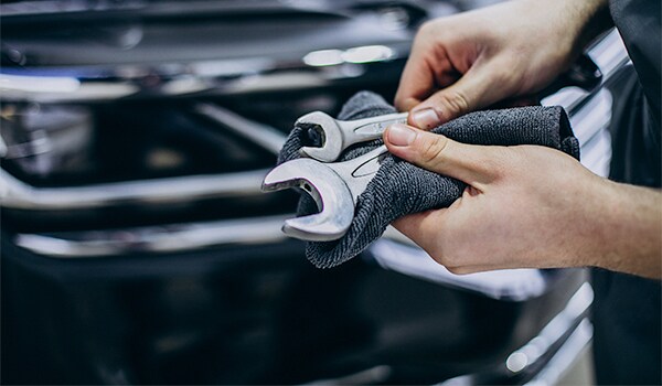Basic Car Maintenance and Servicing Checklist | West Broad Volkswagen | Car Technician Standing in Front of an Open Hood with Tools in Hand