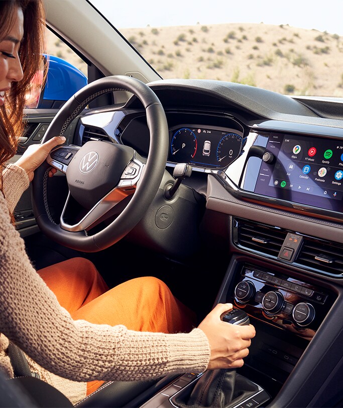 Best MPG At West Broad VW in Richmond, VA | A woman sitting in the drivers seat of a 2023 Volkswagen Taos is putting her car in park