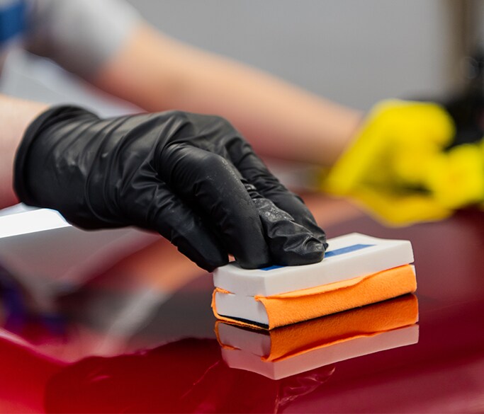 What is Paintless Dent Repair? | West Broad VW | Hand polishing the top coat of a red car with white & orange sponge