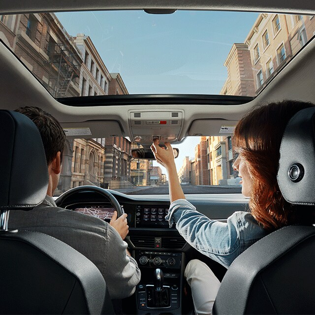 Things to Check When Buying a Used Car | West Broad Volkswagen in Richmond, VA | Interior of 2021 Volkswagen Jetta with Woman in Passenger Seat Toggling Sunroof Open while Man in Driver's Seat Uses Dashboard GPS to Navigate While Driving