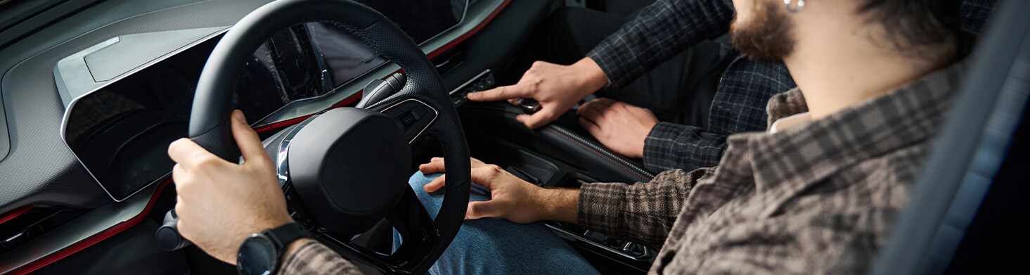 Defining GAP Insurance at West Broad Volkswagen in Richmond, VA | Two people sitting in the front row of a new car while touching the buttons