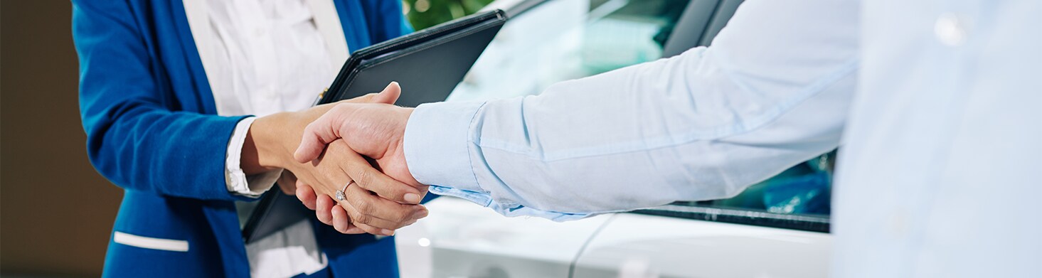 Defining GAP Insurance at West Broad Volkswagen in Richmond, VA | Man and woman shaking hands while woman is holding a black leather folder