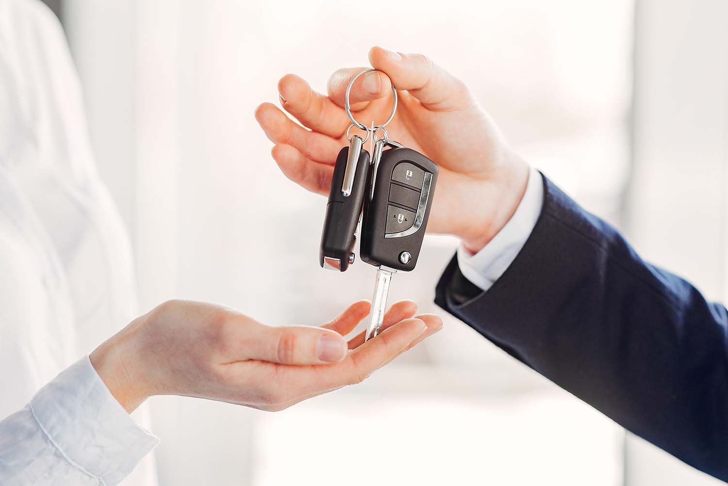 High Cost of Replacing a Car Key | West Broad Volkswagen | Dealership employee handing new keys over to customer