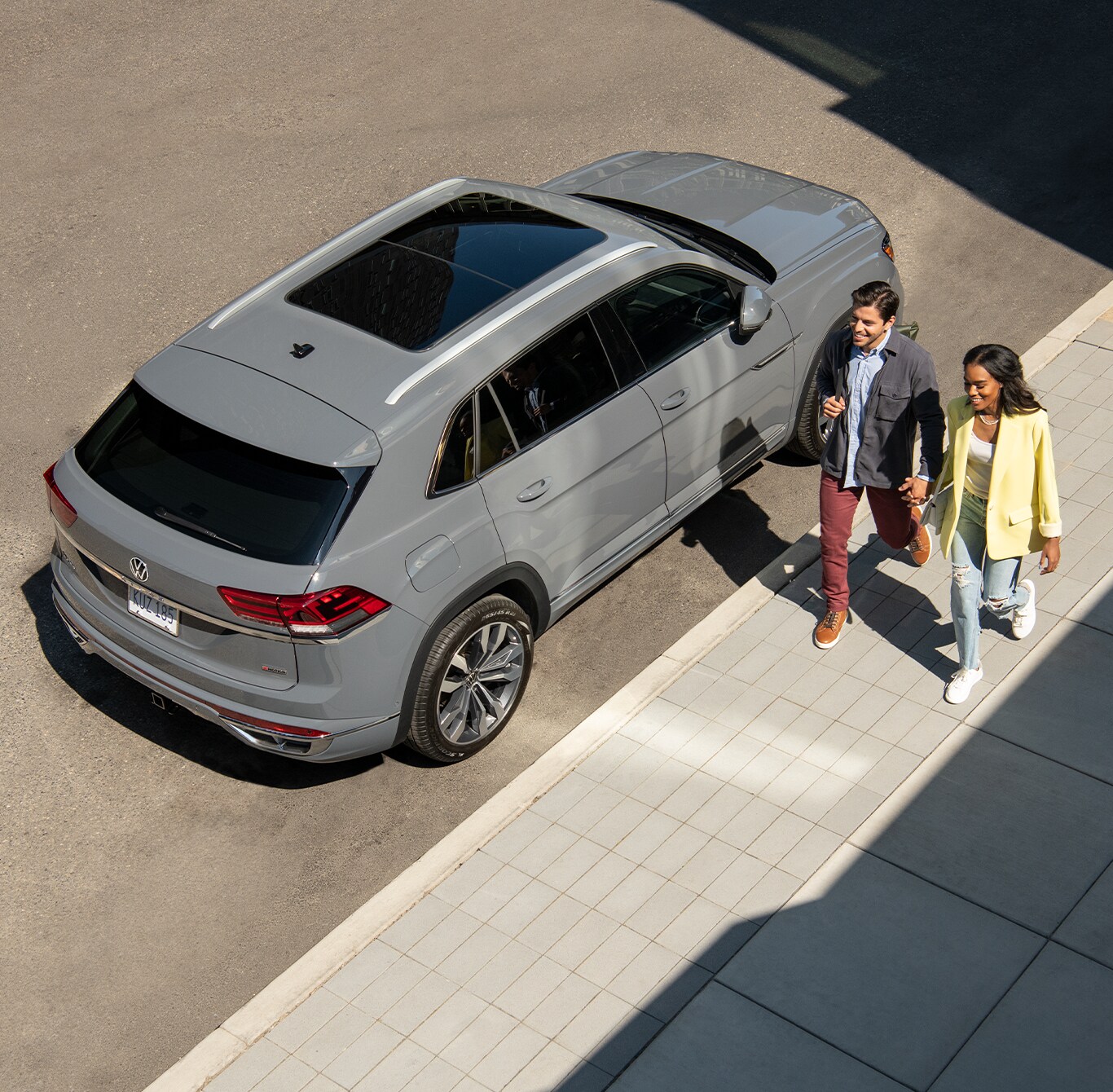 Model Features of the 2022 Volkswagen Atlas at West Broad Volkswagen | Arial view of a Matte Grey Volkswagen Atlas parked on the side of the road with a couple walking beside it holding hands