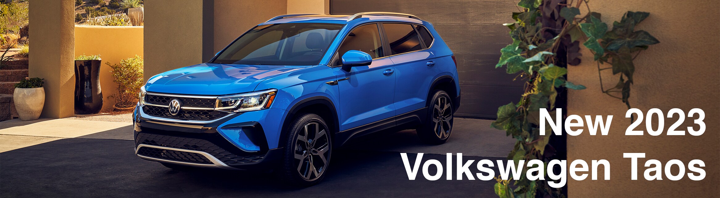 Model Features of the 2023 Volkswagen Taos at West Broad VW | Blue Volkswagen Taos parked outside driveway with title on the right side saying 'New 2023 Volkswagen Taos'