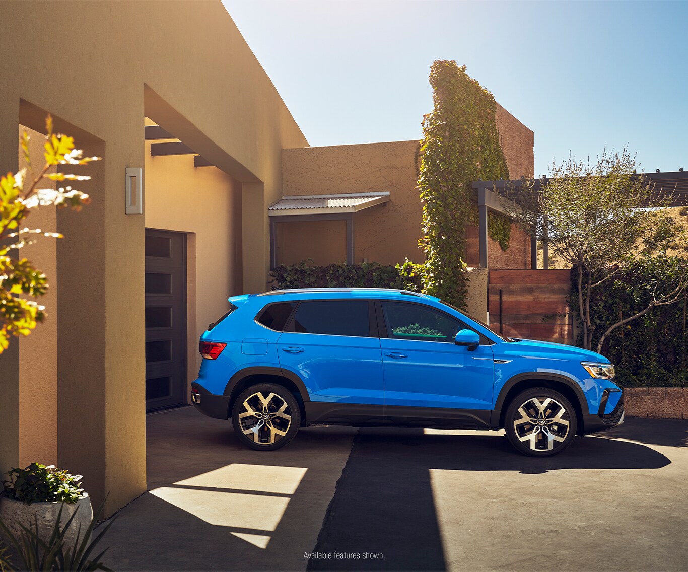 Model Features of the 2023 Volkswagen Taos at West Broad VW | Side view of a blue 2023 Volkswagen Taos parked outside of driveway with the sun shining