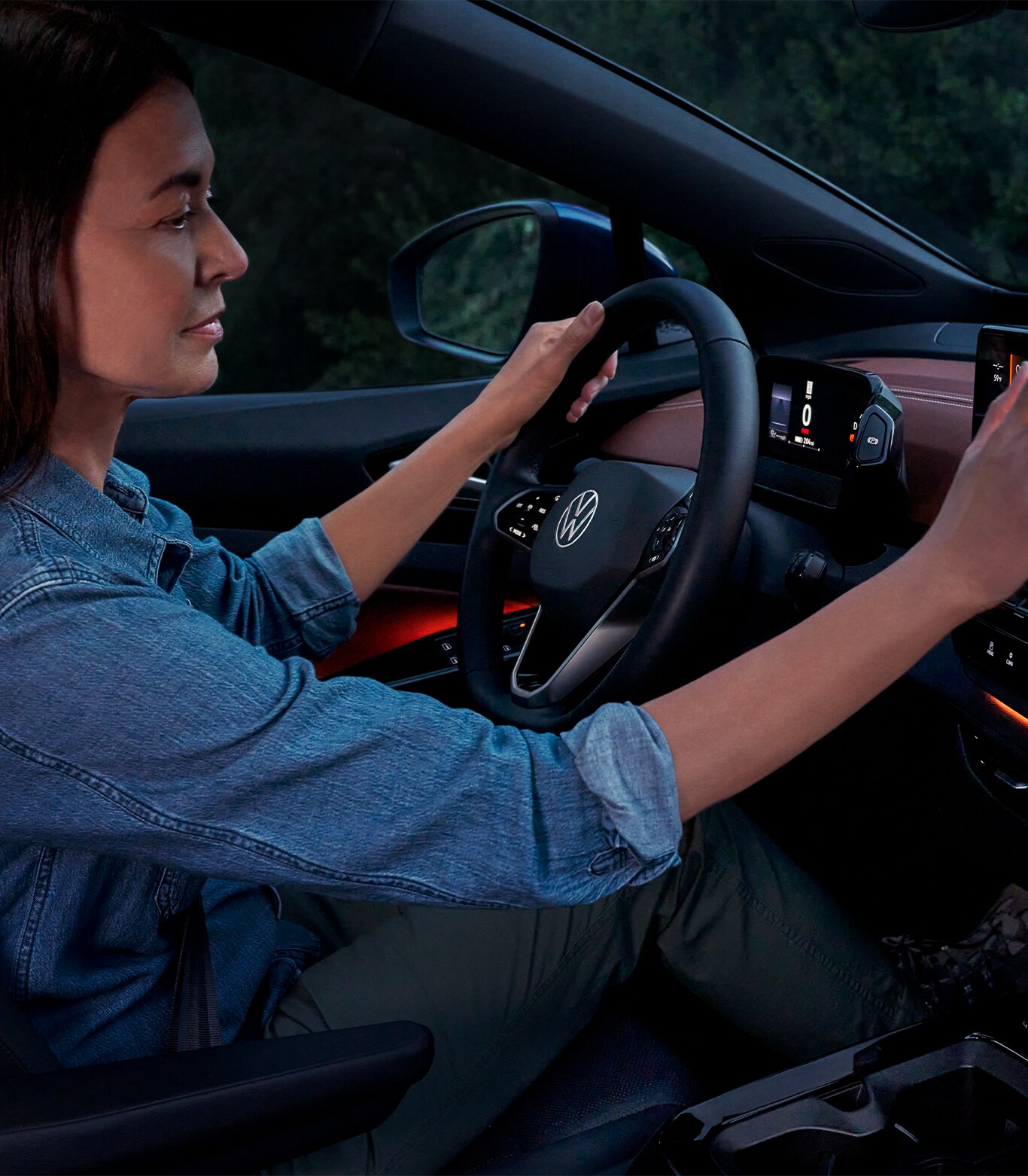 Android Auto vs. Apple CarPlay at West Broad VW in Richmond, VA | Woman driving her car at night while interacting with the center console