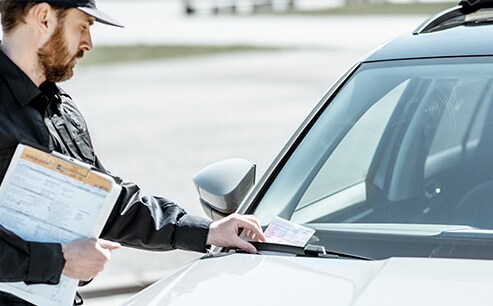 Why You Shouldn’t Drive Around with a Chipped Windshield at West Broad VW in Richmond, VA | Policeman putting a ticket on car windshield