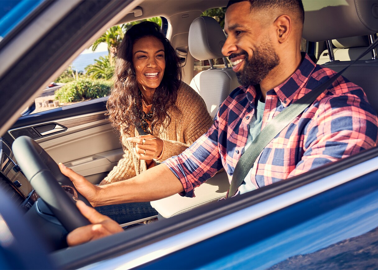 Android Auto vs. Apple CarPlay at West Broad VW in Richmond, VA | Man and woman driving a blue Volkswagen while smiling