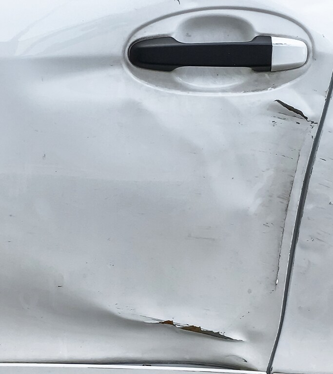 What is Paintless Dent Repair? | West Broad VW | White car door with a big dent and paint chip
