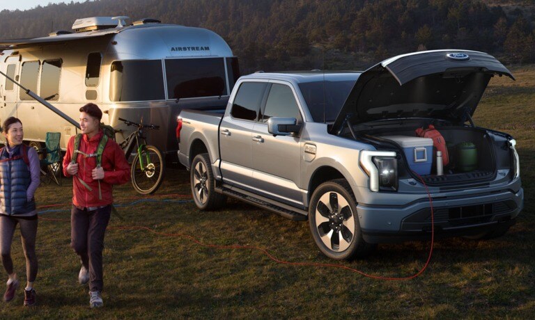 2023 Ford F-150 Lightning in a camp site trailering an RV