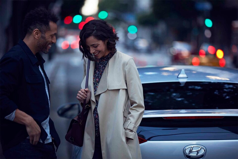 Man and woman talking by Hyundai car parked on street.jpeg