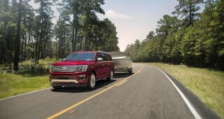 Ford Explorer Model Research A red Ford Expedition hauling a boat through the countryside