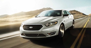 Ford Taurus Model Research A silver Ford Taurus driving down the country road