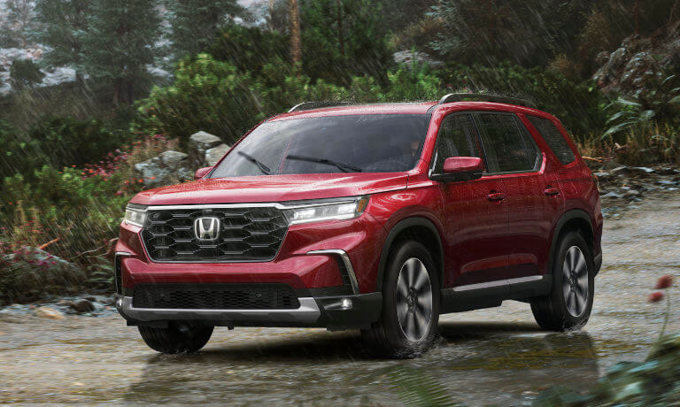2025 Honda Pilot driving in a rainy forest