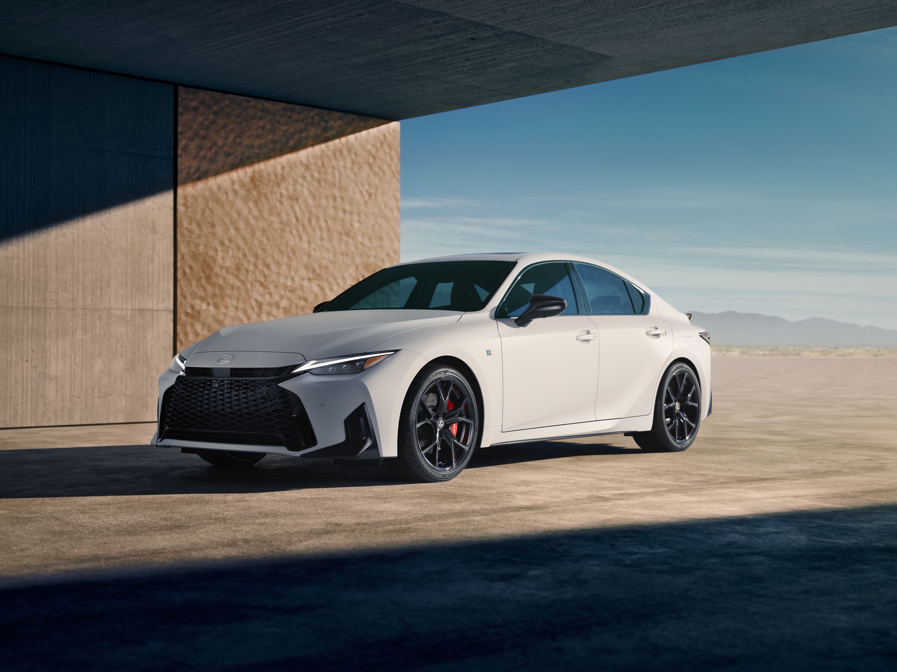 Which Lexus is right for me? White Lexus IS F Sport luxury sports sedan parked under a modern architectural concrete structure.