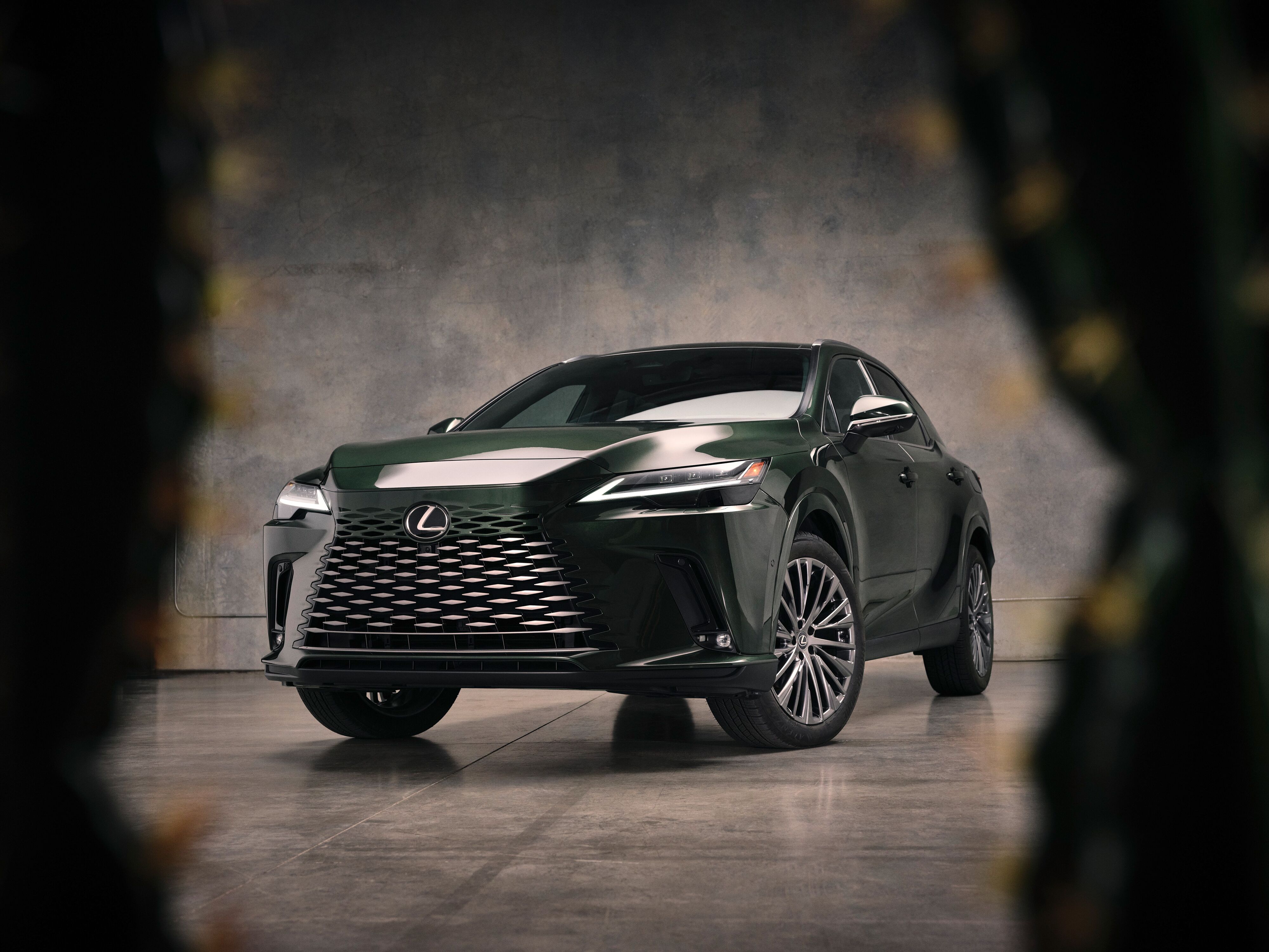 Which Lexus is right for me? Front three-quarter view of a dark green Lexus RX luxury crossover in a modern studio setting.