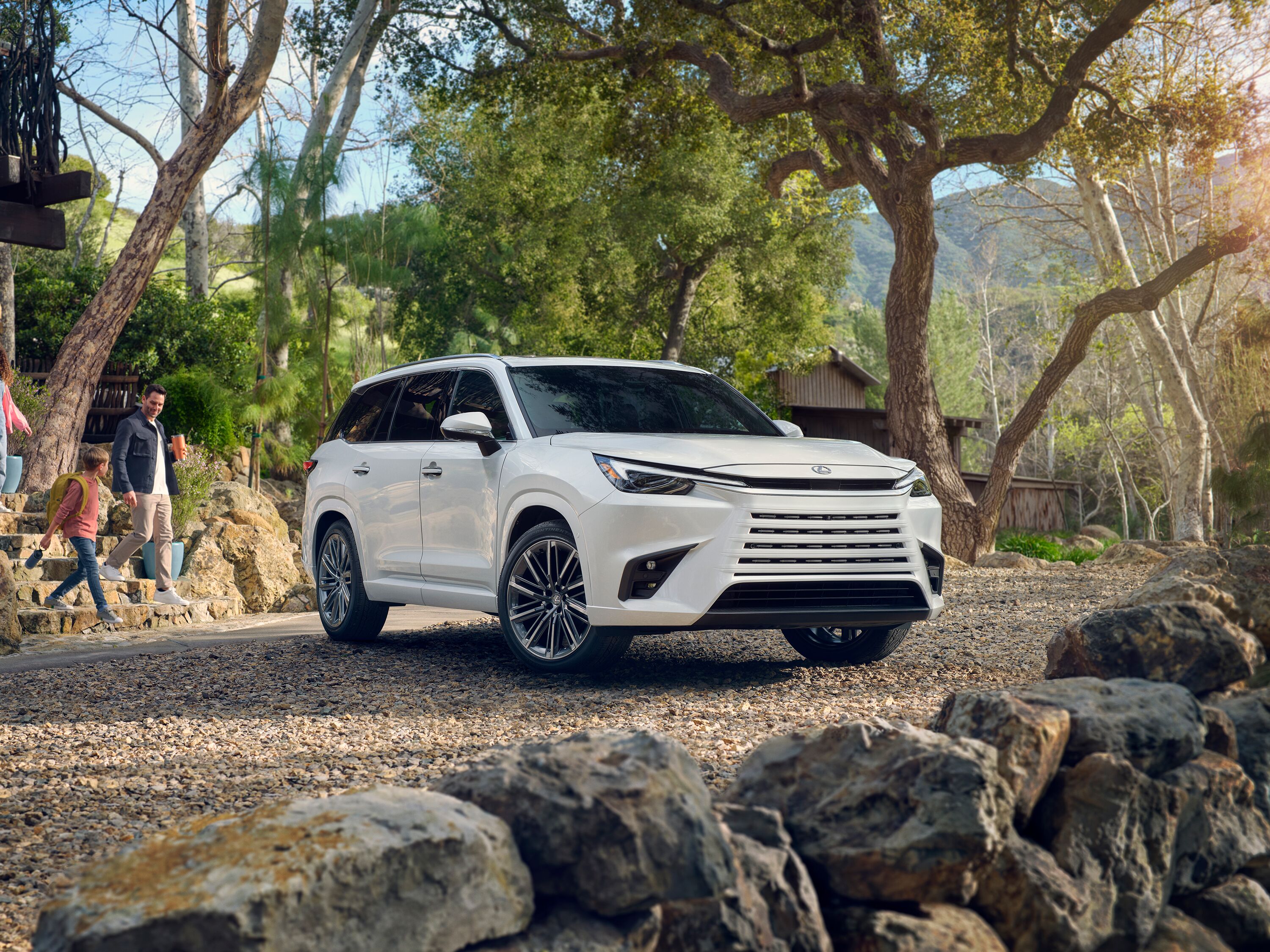 Which Lexus is right for me? White Lexus TX three-row luxury SUV parked on a cobblestone driveway with a family walking nearby.