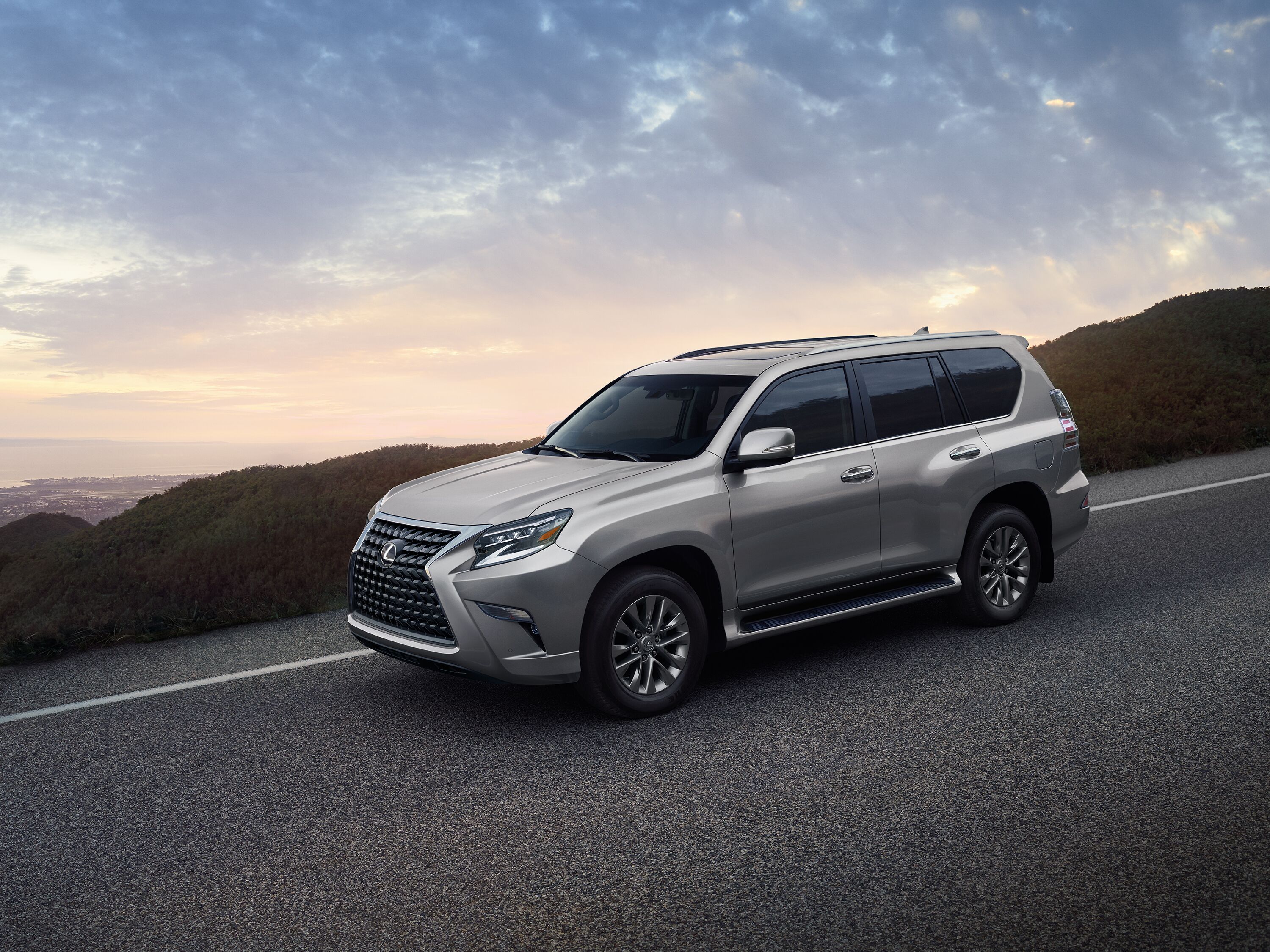 Which Lexus is right for me? Silver Lexus GX luxury SUV parked on a scenic mountain highway overlooking the coastline at dawn.