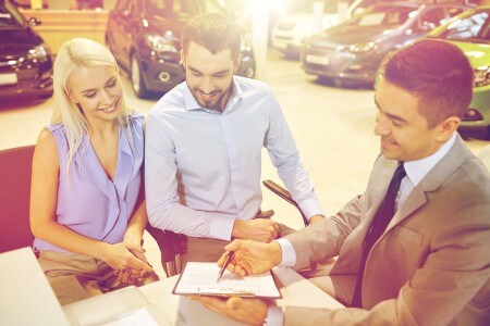 Man and woman look at vehicle trade-in paperwork